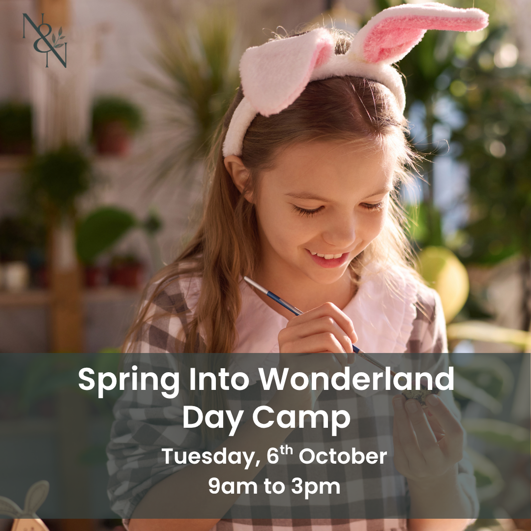 Young girl wearing bunny ears writes with a pencil at an outdoor craft table; Nature & Nurture watermark in the top-left and a text overlay reads 'Spring Into Wonderland Day Camp' with date and time.